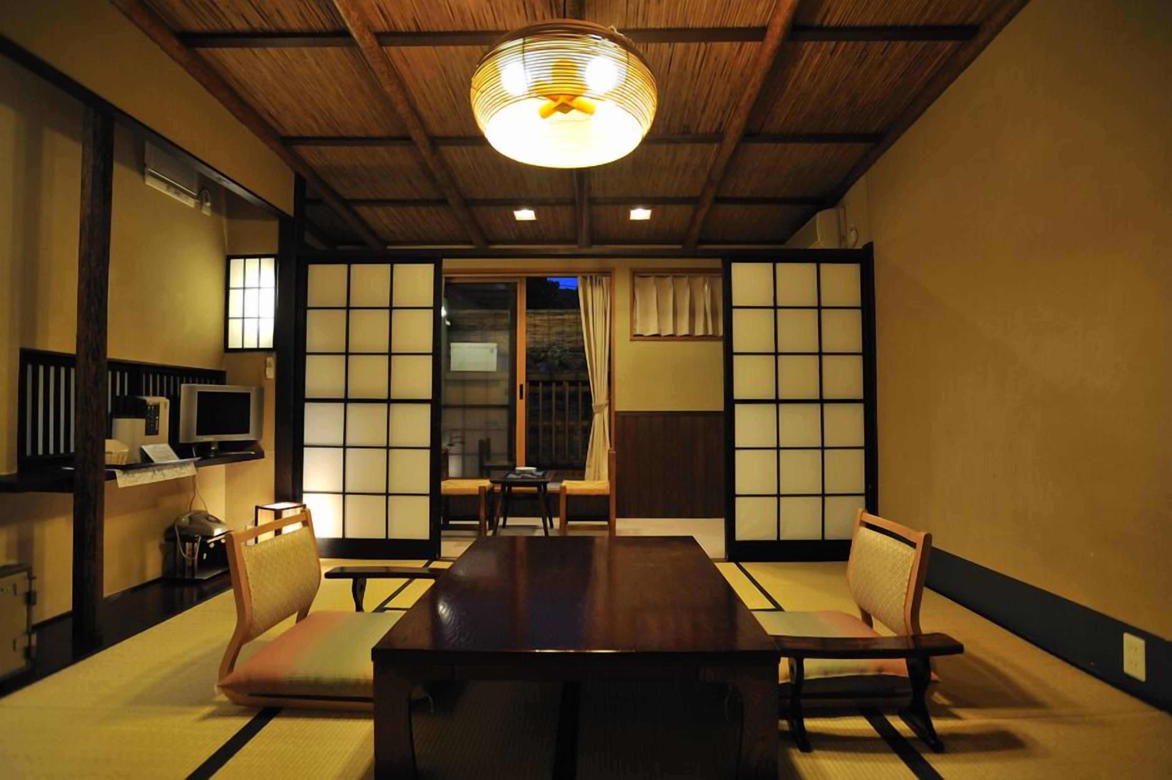 Una habitación japonesa tradicional con suelo de tatami, una mesa baja y puertas correderas.