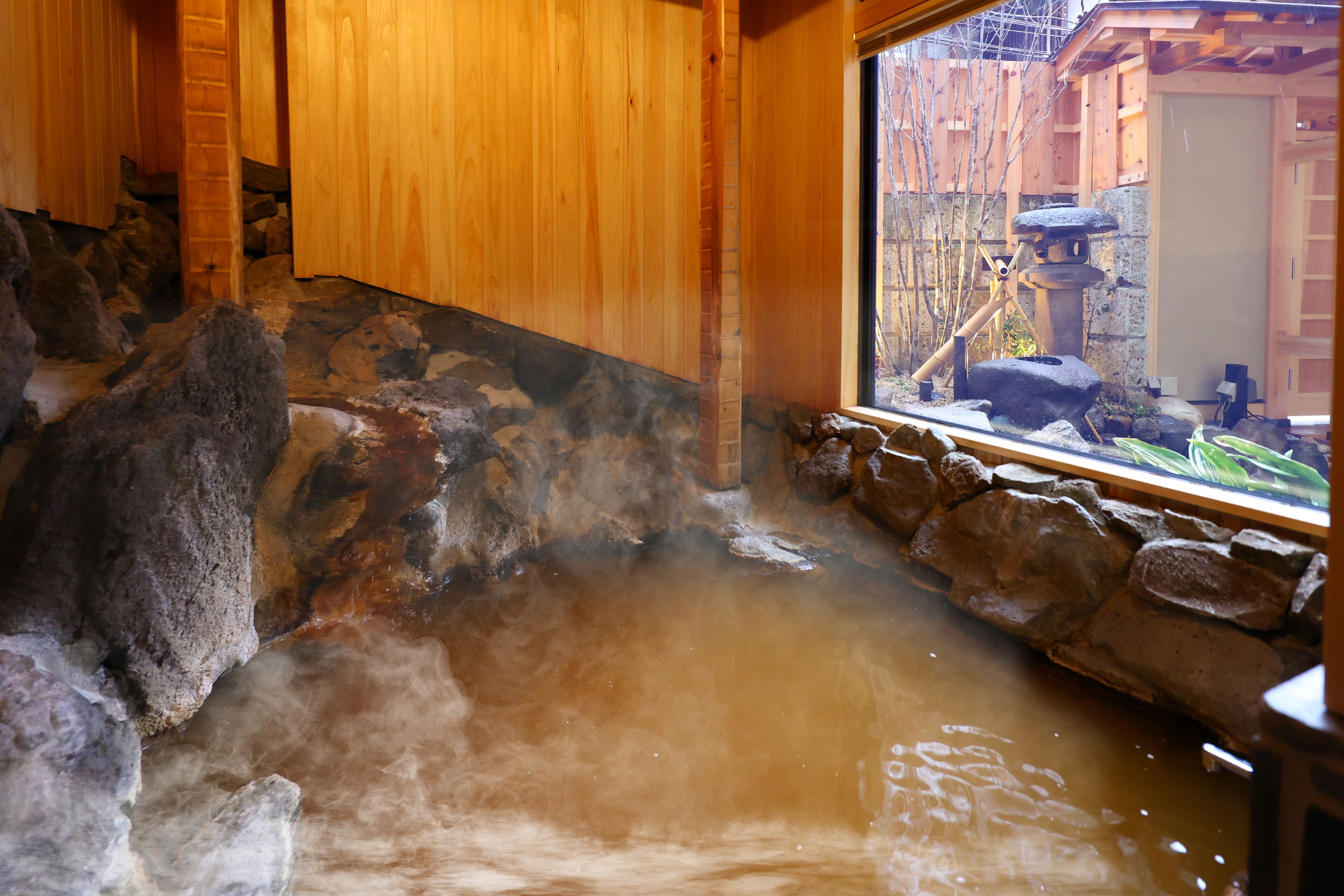 Un área de baños termales con paredes de madera y una pared de piedra.