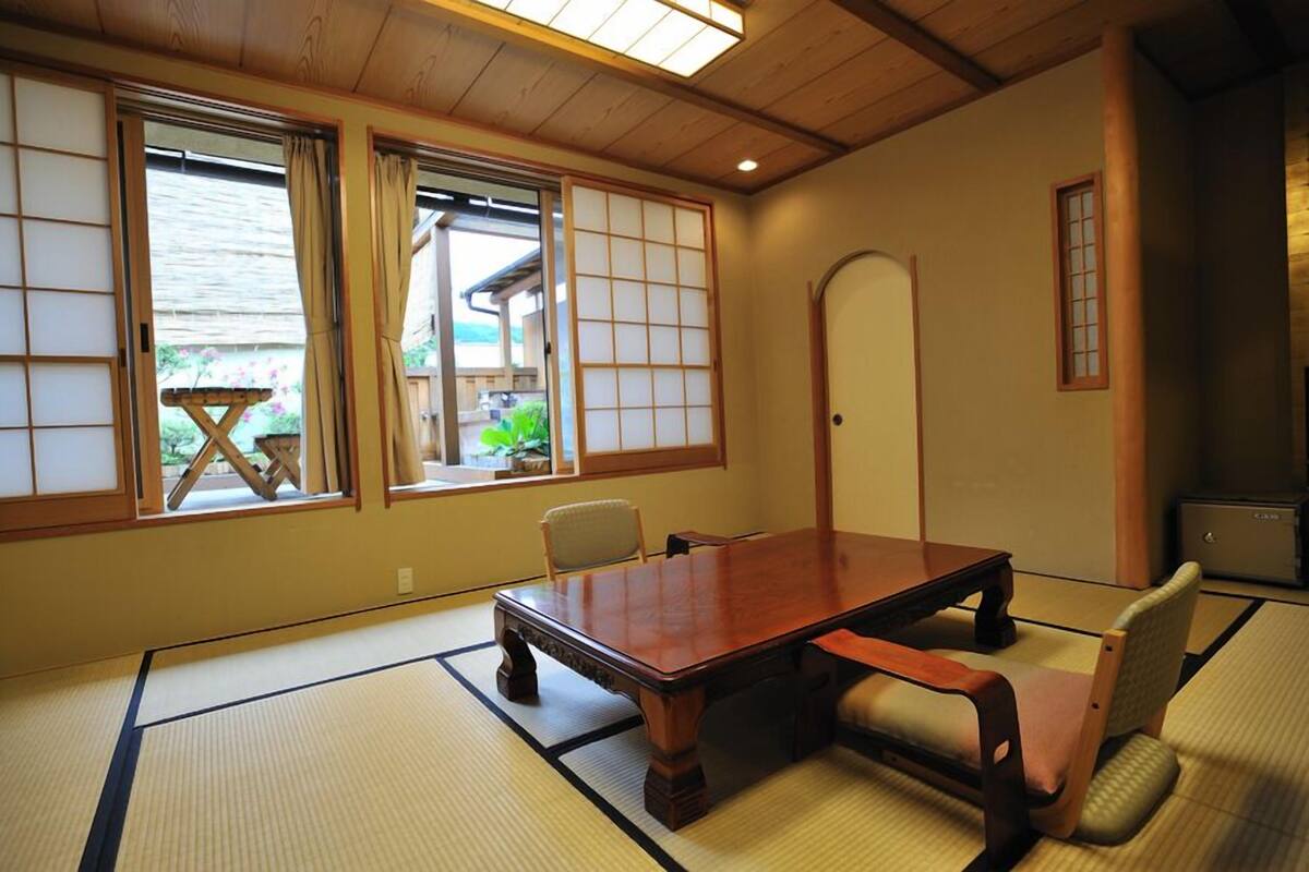 A traditional Japanese room with tatami flooring, a low wooden table, and sliding doors.