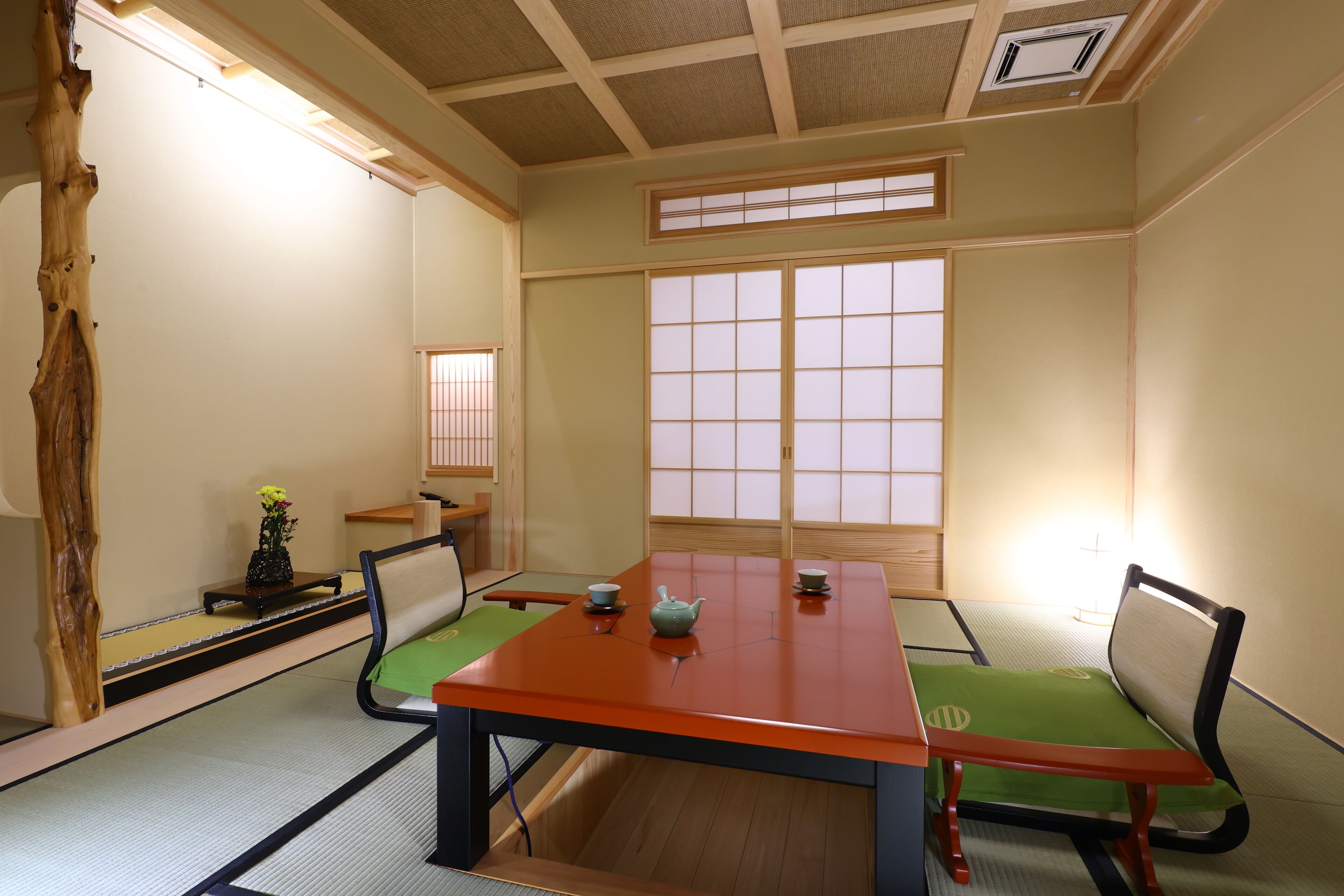 Una habitación japonesa tradicional con suelo de tatami, una mesa baja y puertas correderas shoji.