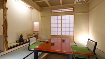 Una habitación japonesa tradicional con suelo de tatami, una mesa baja y puertas correderas shoji.