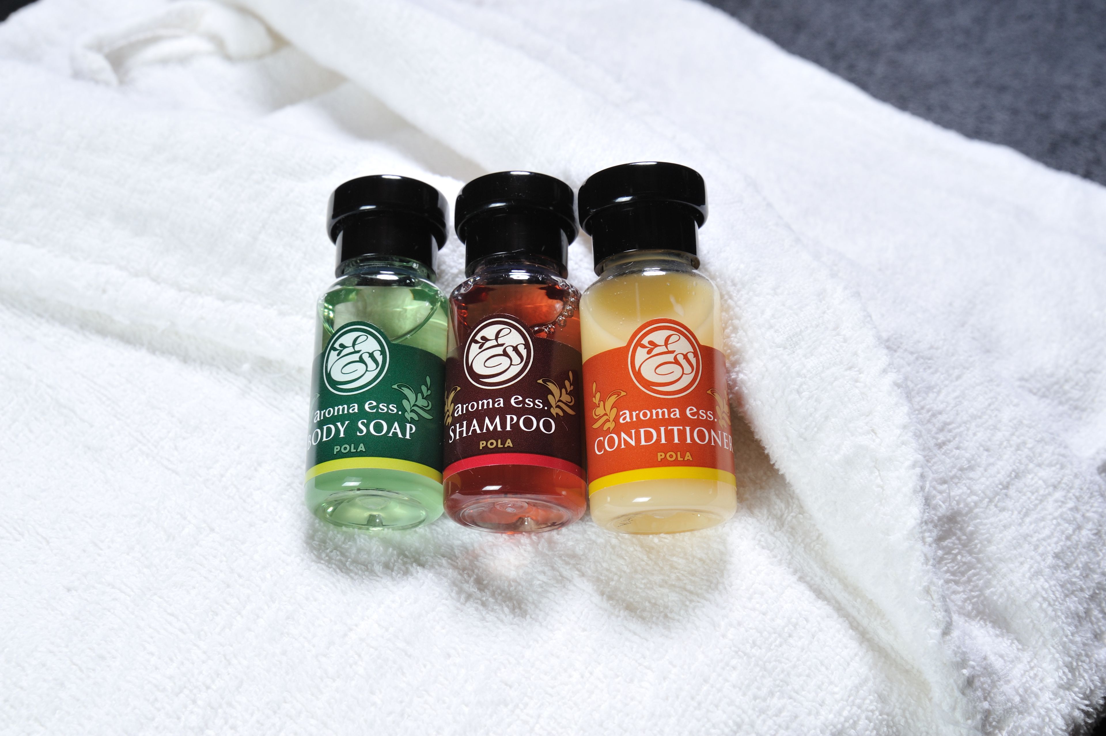 Three bottles of body care products on a white towel.