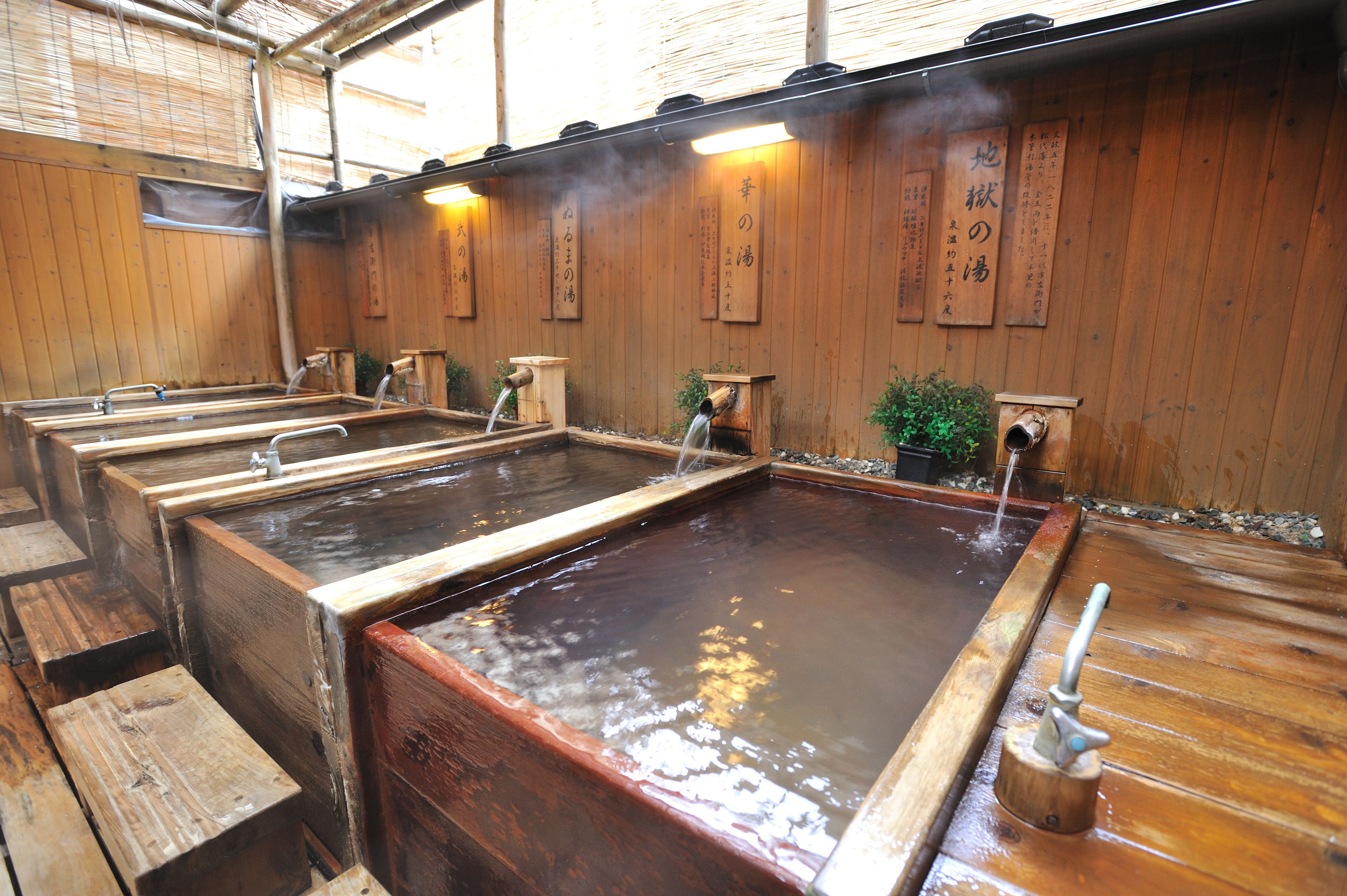 A traditional Japanese onsen with multiple wooden tubs and a wooden interior.