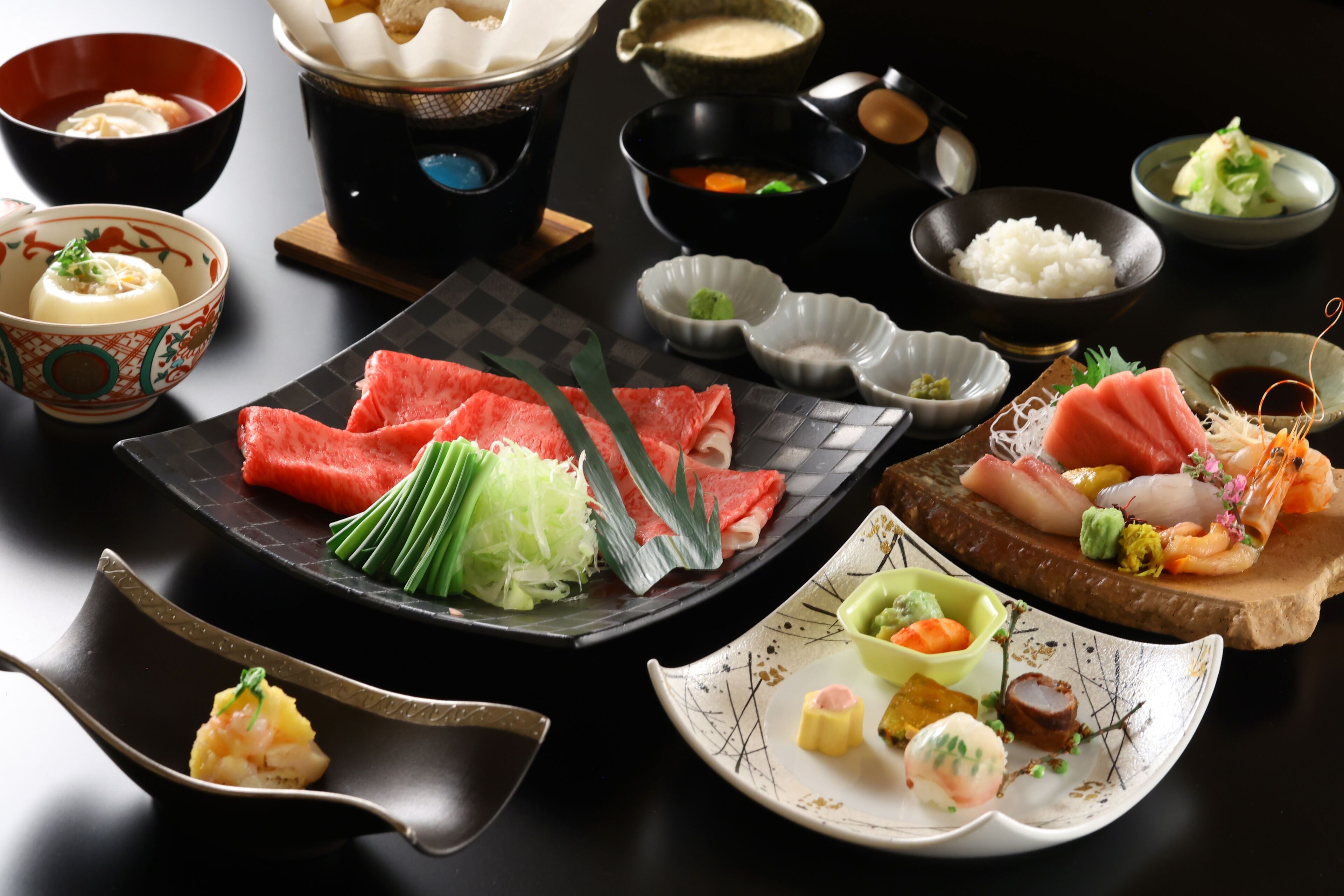 A variety of Japanese dishes including sashimi, rice, and soup, arranged on a table.