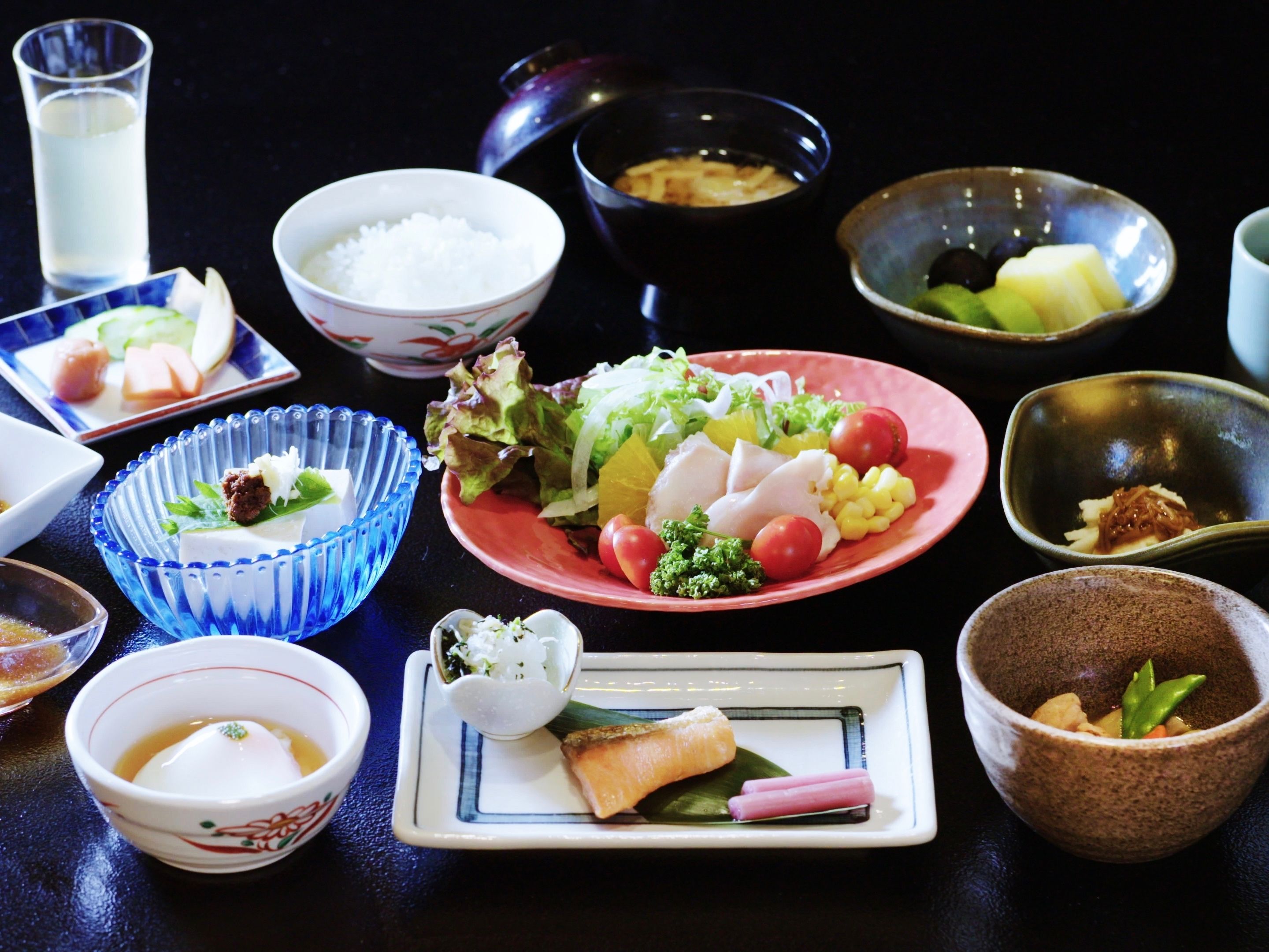 Verschiedene Gerichte, darunter Sushi, Sashimi und Gemüse, auf einem Tisch.