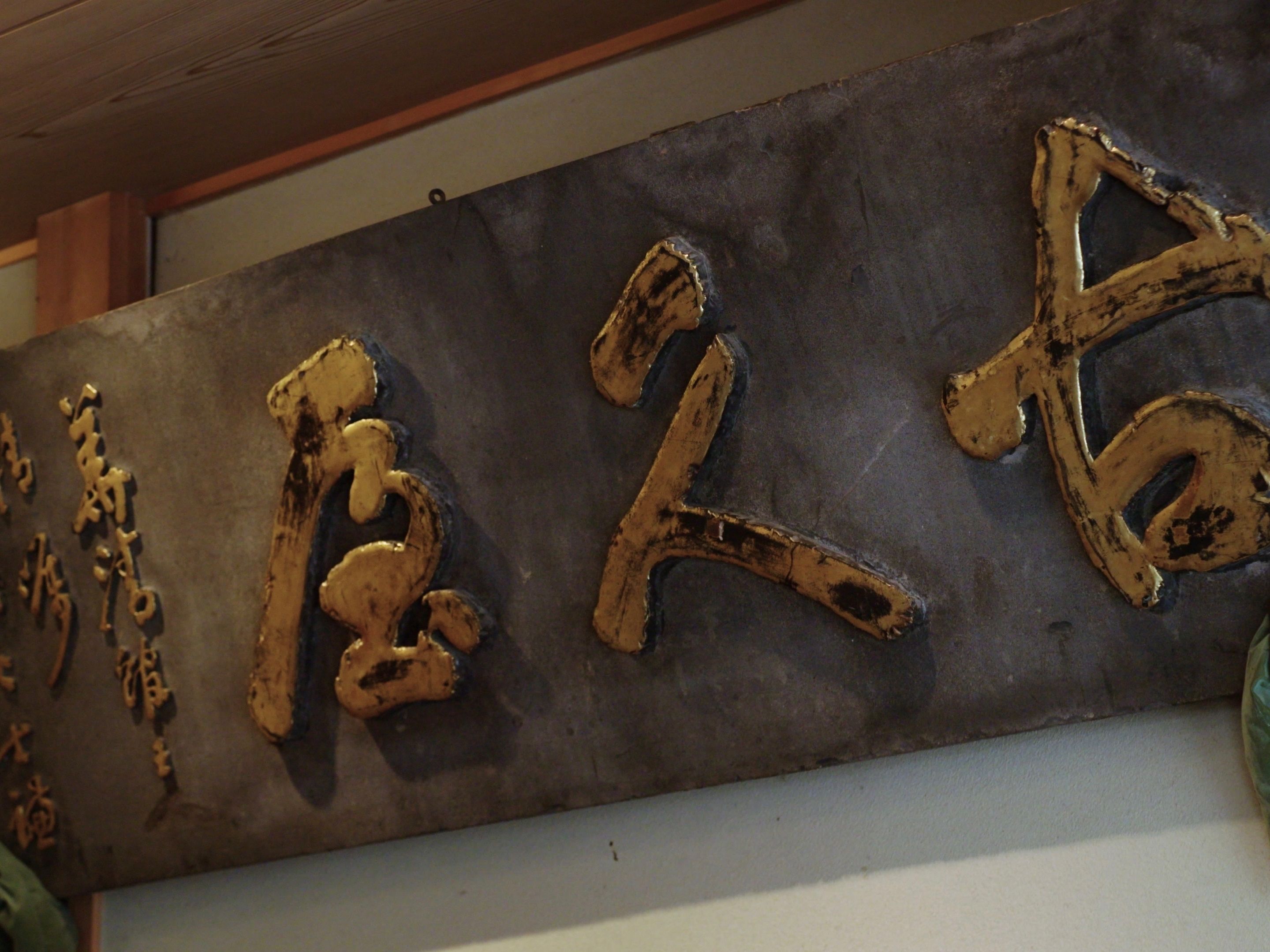 A metal sign with large, weathered characters.