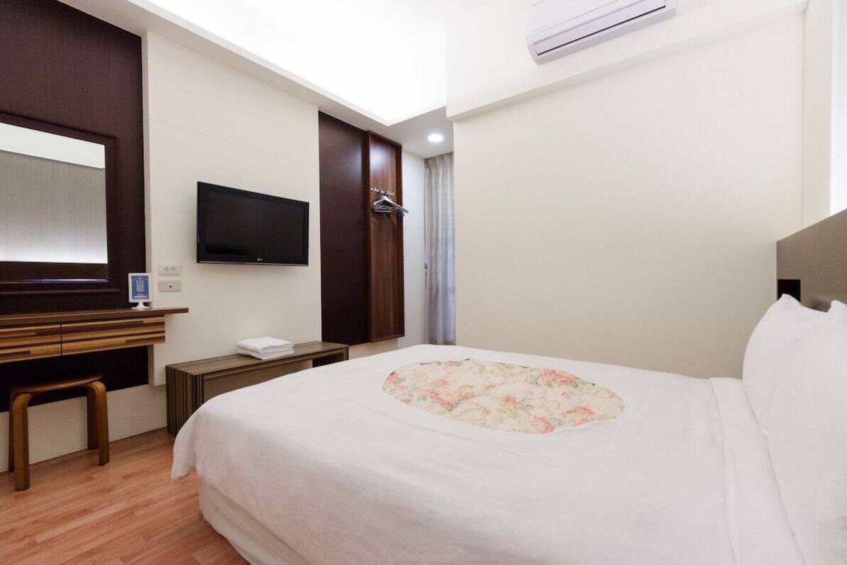 Een hotelkamer met een bed, bureau met stoel, televisie en een kledingkast.
