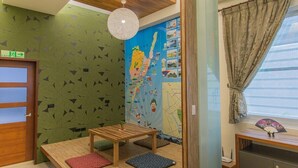 Une pièce avec une table en bois, une carte accrochée au mur et une fenêtre avec des rideaux.