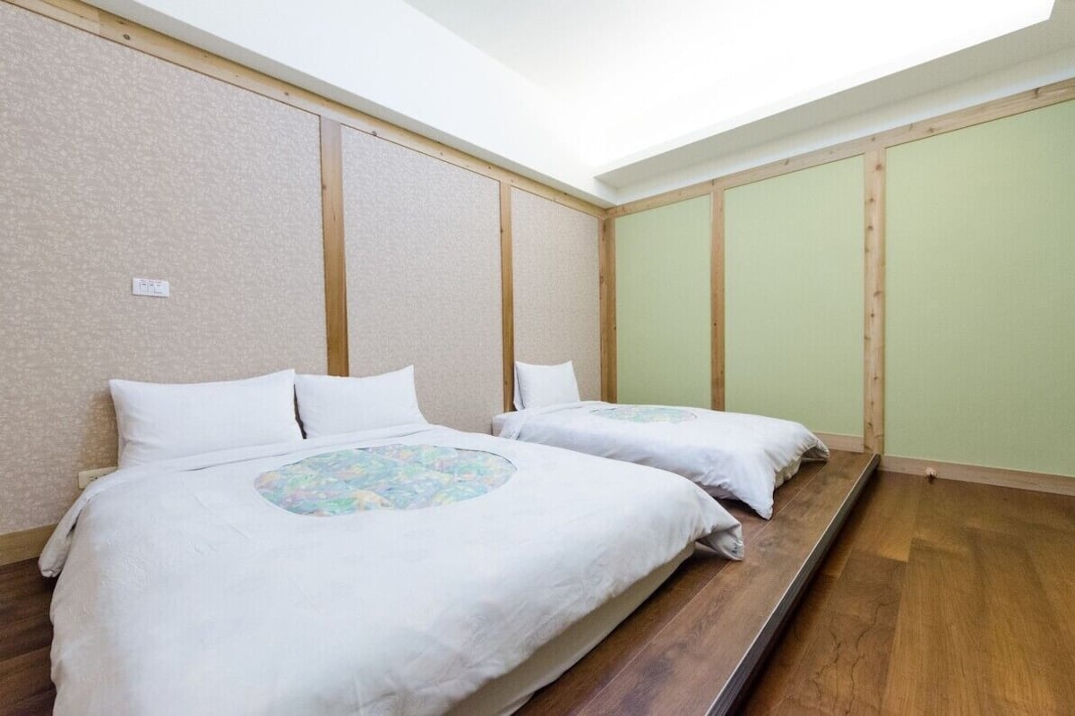 Een kamer met twee bedden, houten vloeren en een dakvenster.