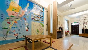 Un hall d’hôtel avec une grande carte accrochée au mur, une table en bois et un comptoir d’accueil.