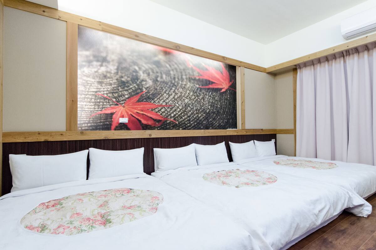 Een hotelkamer met een groot bed, een houten hoofdbord en een wanddecoratie met rode bladeren.