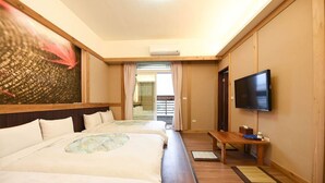 Une chambre d’hôtel avec deux lits, une télévision et une porte coulissante donnant sur un balcon.