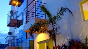 A multi-story building with balconies, a well-lit entrance, and potted plants. - The Orient Beach Boracay (Boracay Island)