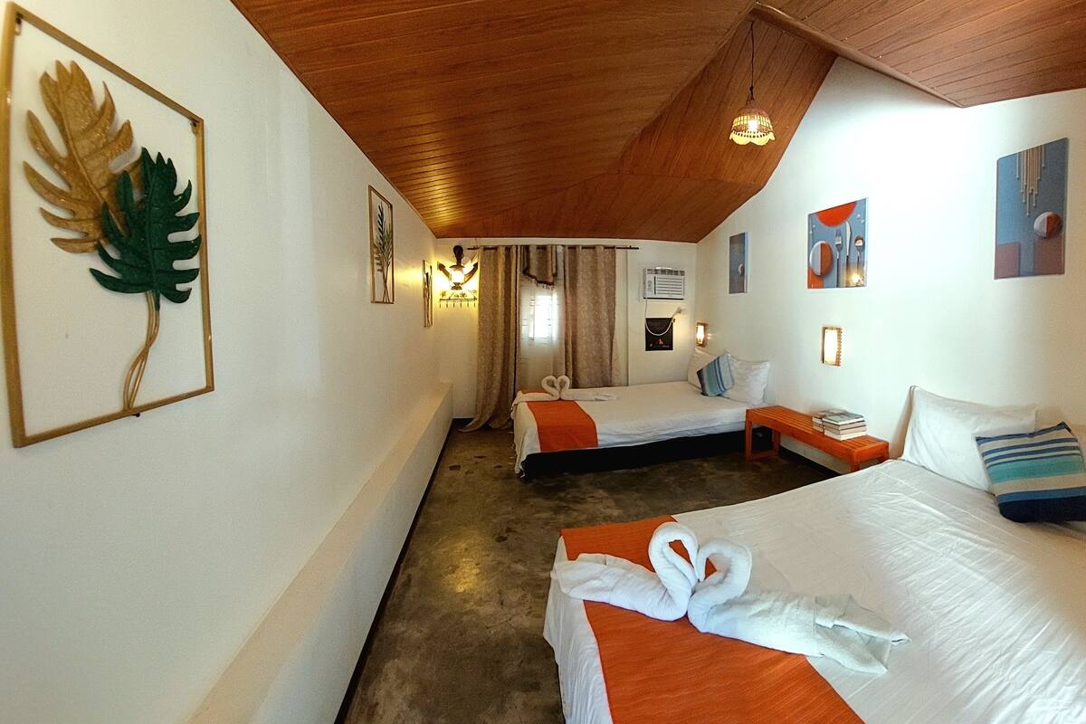 Een hotelkamer met twee bedden, een houten plafond en kunst aan de muur.