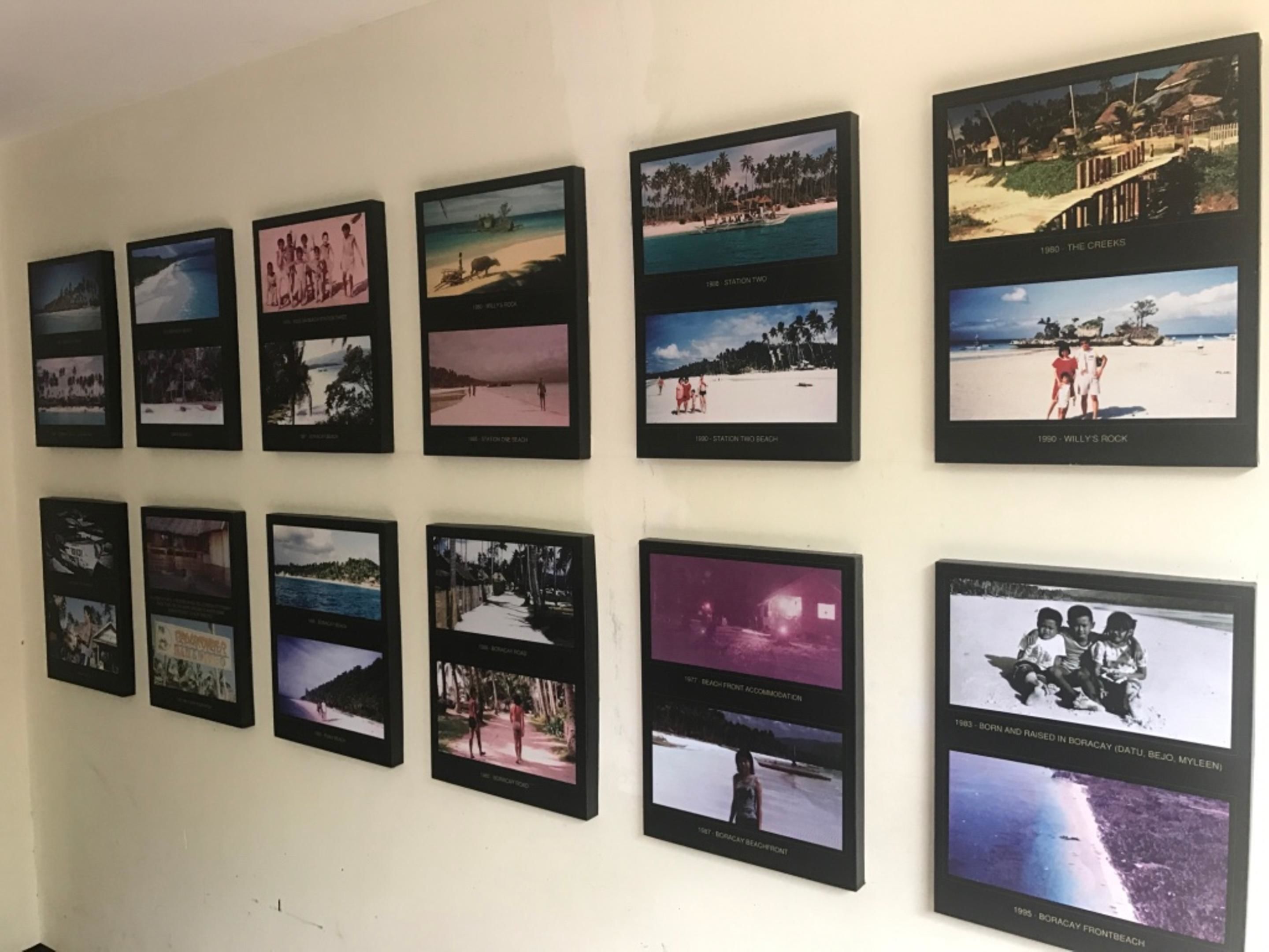 A wall with 15 framed photographs depicting various beach scenes and locations.