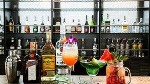 Zona de bar con varias botellas de licores y dos cócteles sobre la barra.