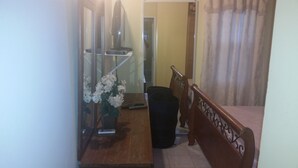 A hallway with a wooden bench, a trash bin, and a vase with white flowers. - Palm Cove - 2 Bedroom Cottage (Montego Bay)