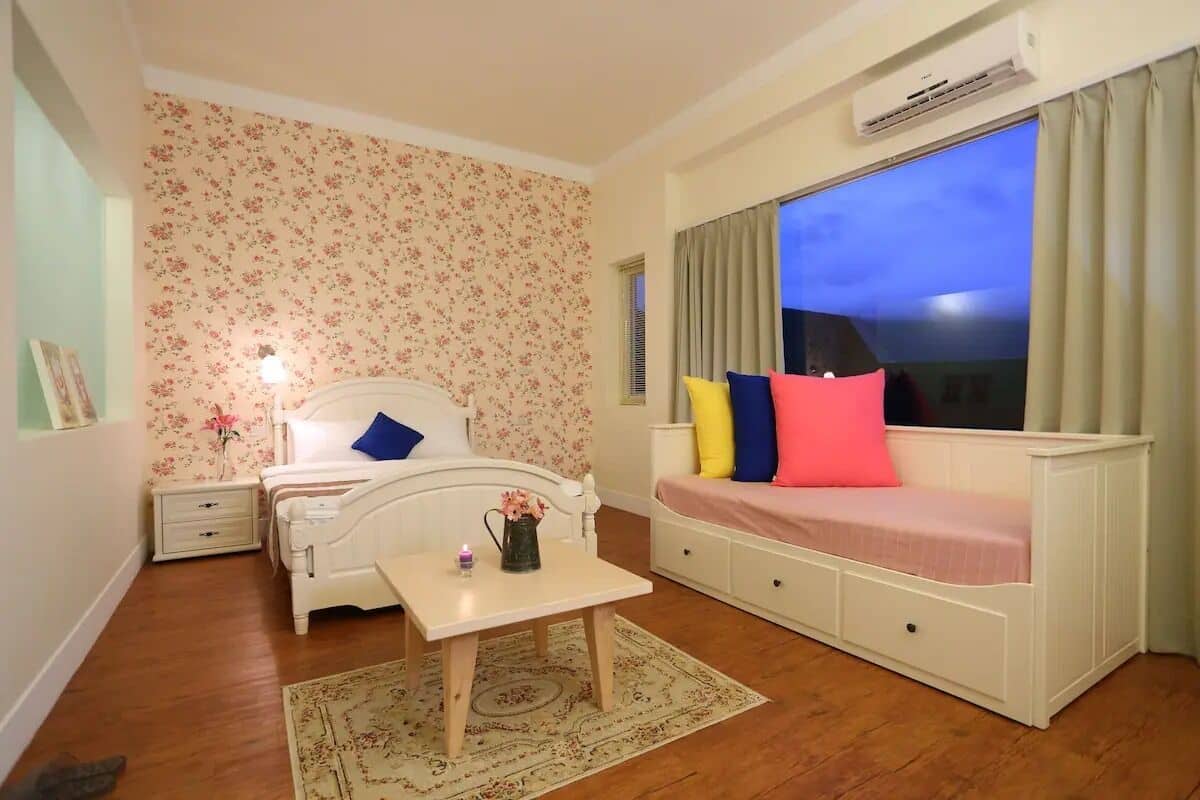 A bedroom with a bed, bedside table, and a window with curtains.