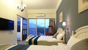 Habitación de hotel con dos camas, televisión, araña y balcón con vistas.