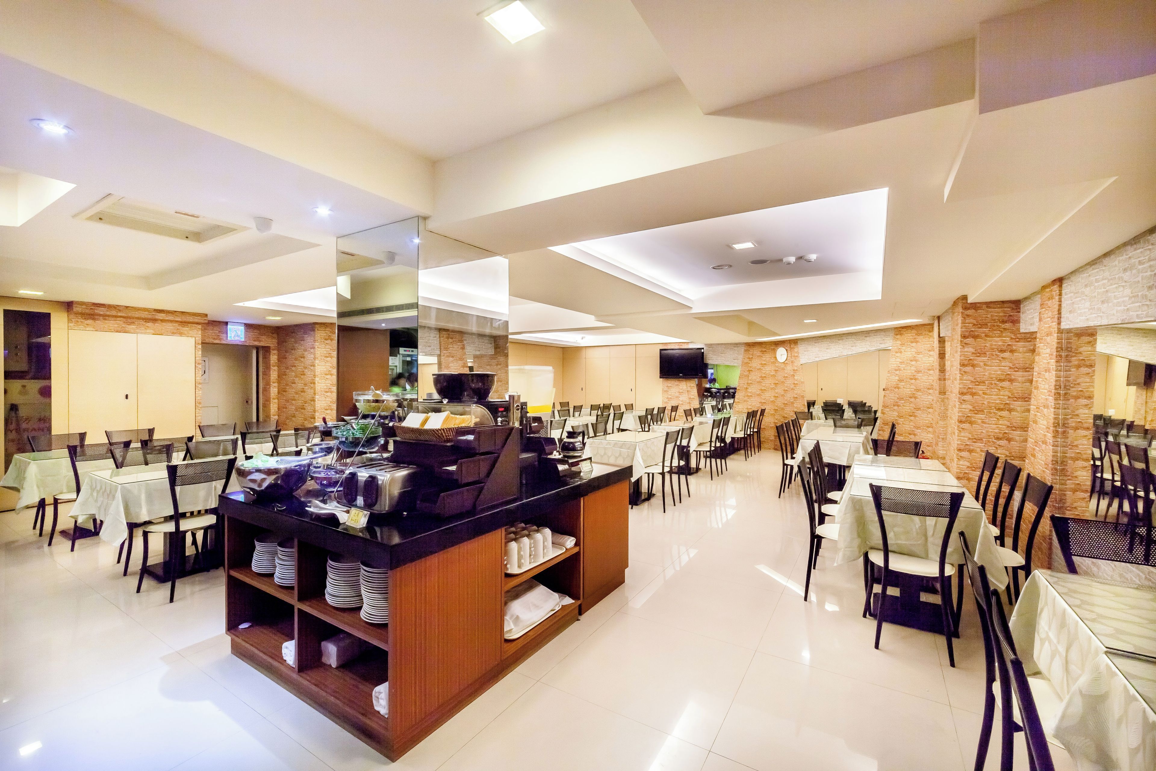 A spacious dining area with multiple tables and chairs, a buffet station, and a modern ceiling design.