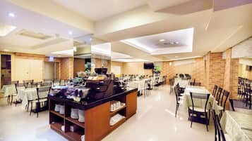 A spacious dining area with multiple tables and chairs, a buffet station, and a modern ceiling design.