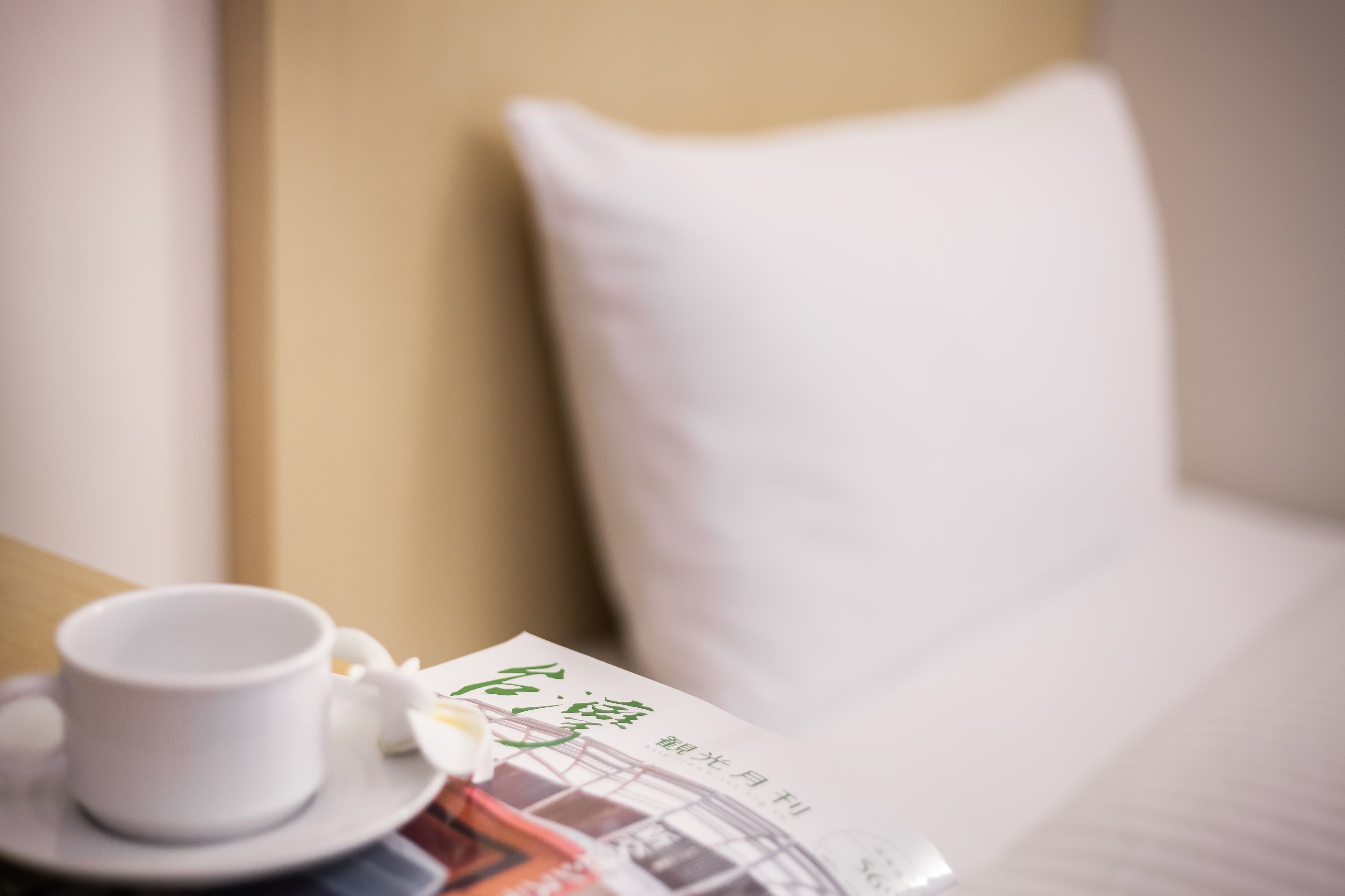 A white cup on a saucer and a menu on a table in a hotel room.
