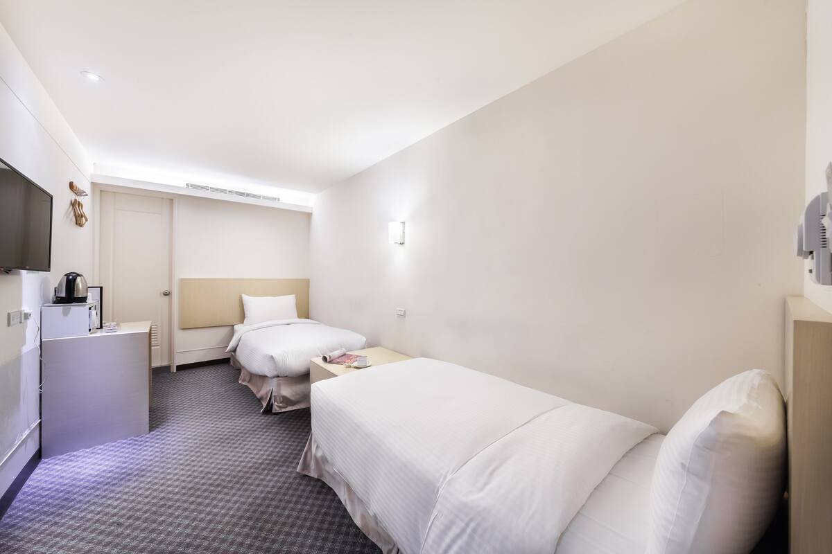 Habitación de hotel con dos camas, un escritorio, un televisor y un minibar.
