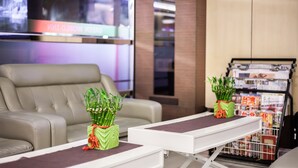 A modern hotel lobby with a leather sofa, a reception desk, and a magazine rack.