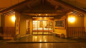 Un edificio japonés tradicional con techo de madera, piso de baldosas y un banco al frente.