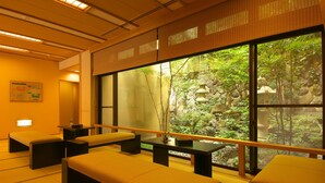 Una habitación tradicional japonesa con suelo de tatami, mesas bajas y cojines.
