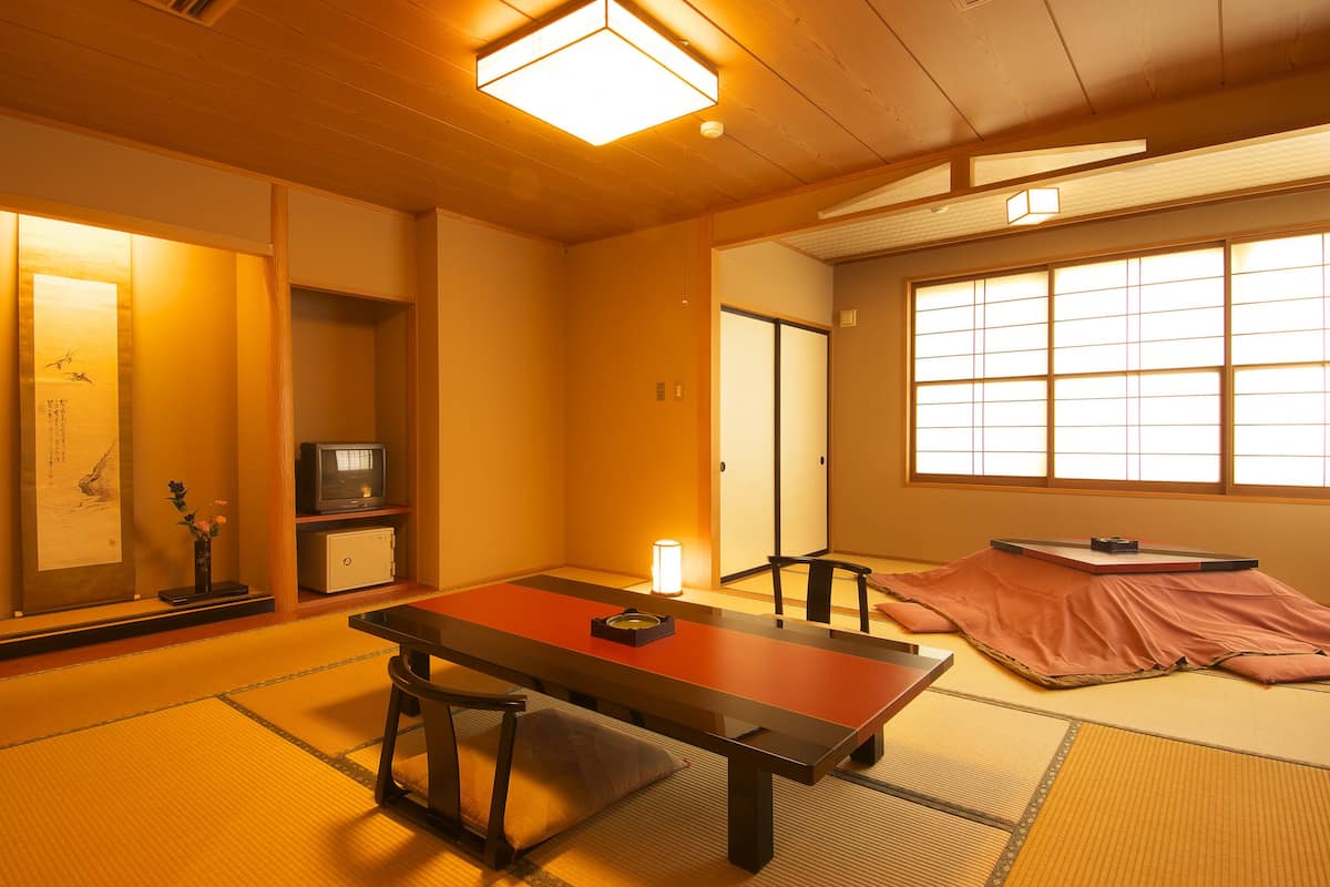 Ein traditioneller japanischer Raum mit Tatami-Böden, einem niedrigen Tisch und verschiebbaren Türen.