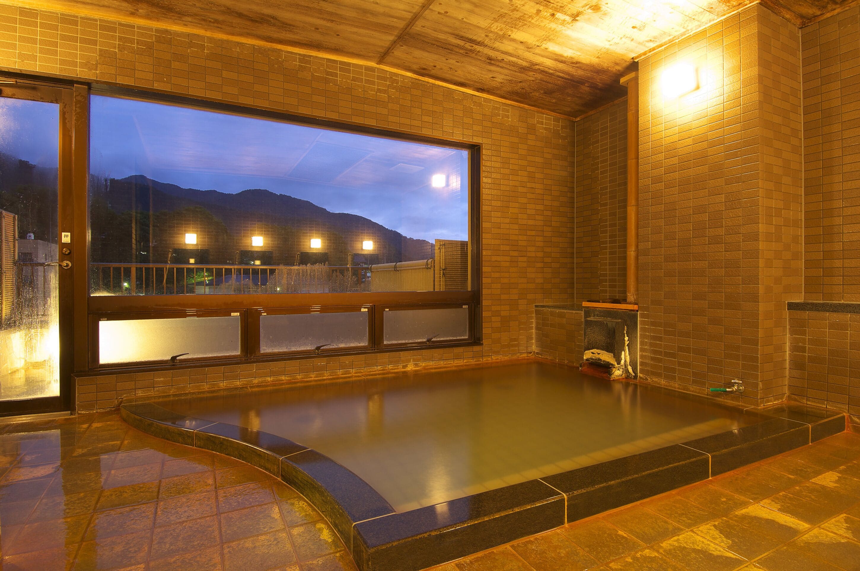 Un jacuzzi con vistas a montañas, una pared de azulejos y un techo de madera.