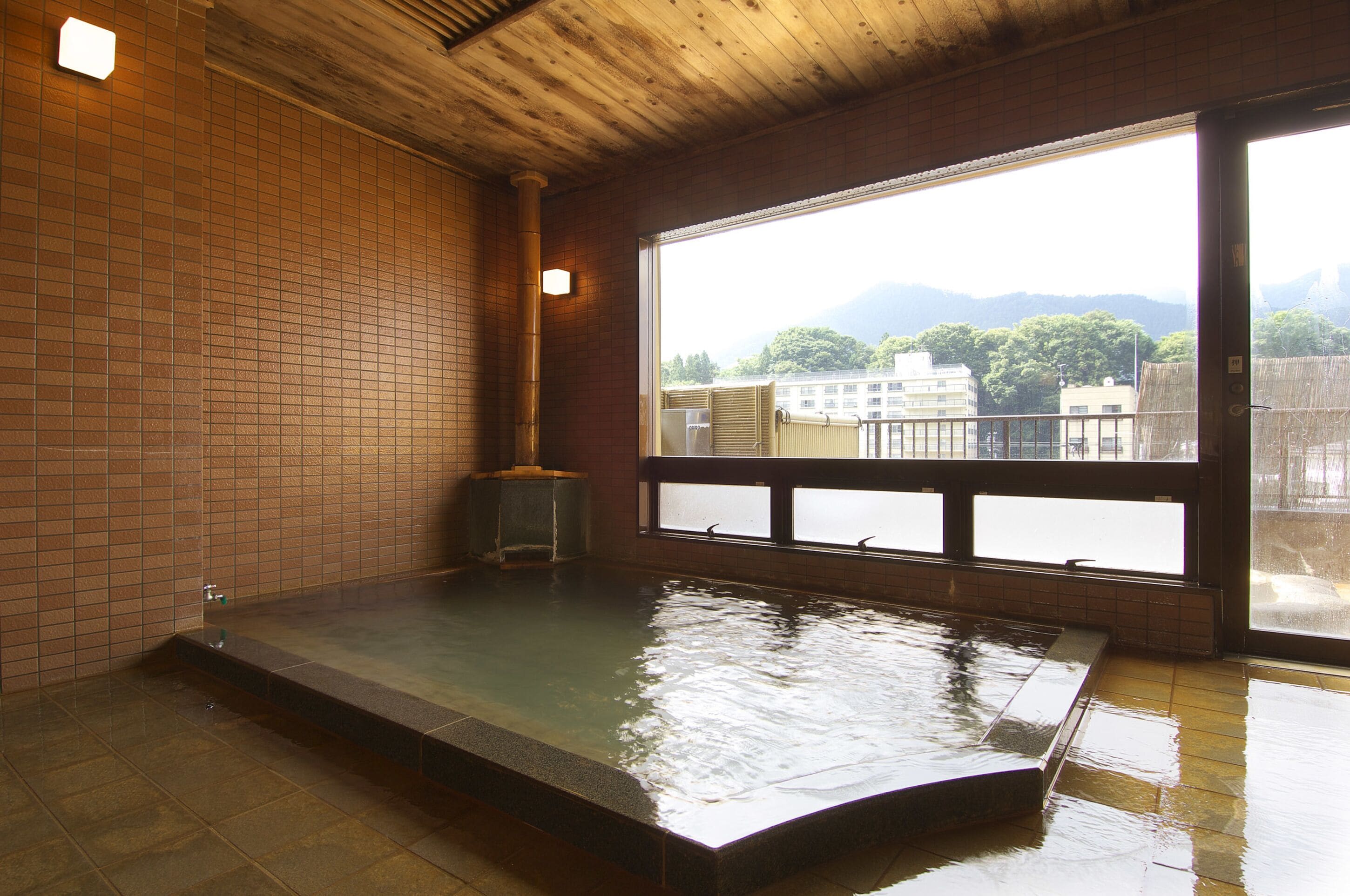 A room with a large window, a wooden ceiling, and a tiled floor.