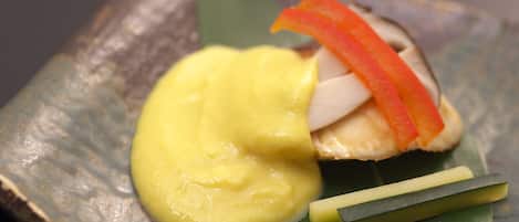 A dish with yellow sauce, red bell pepper, and green garnish on a leaf.