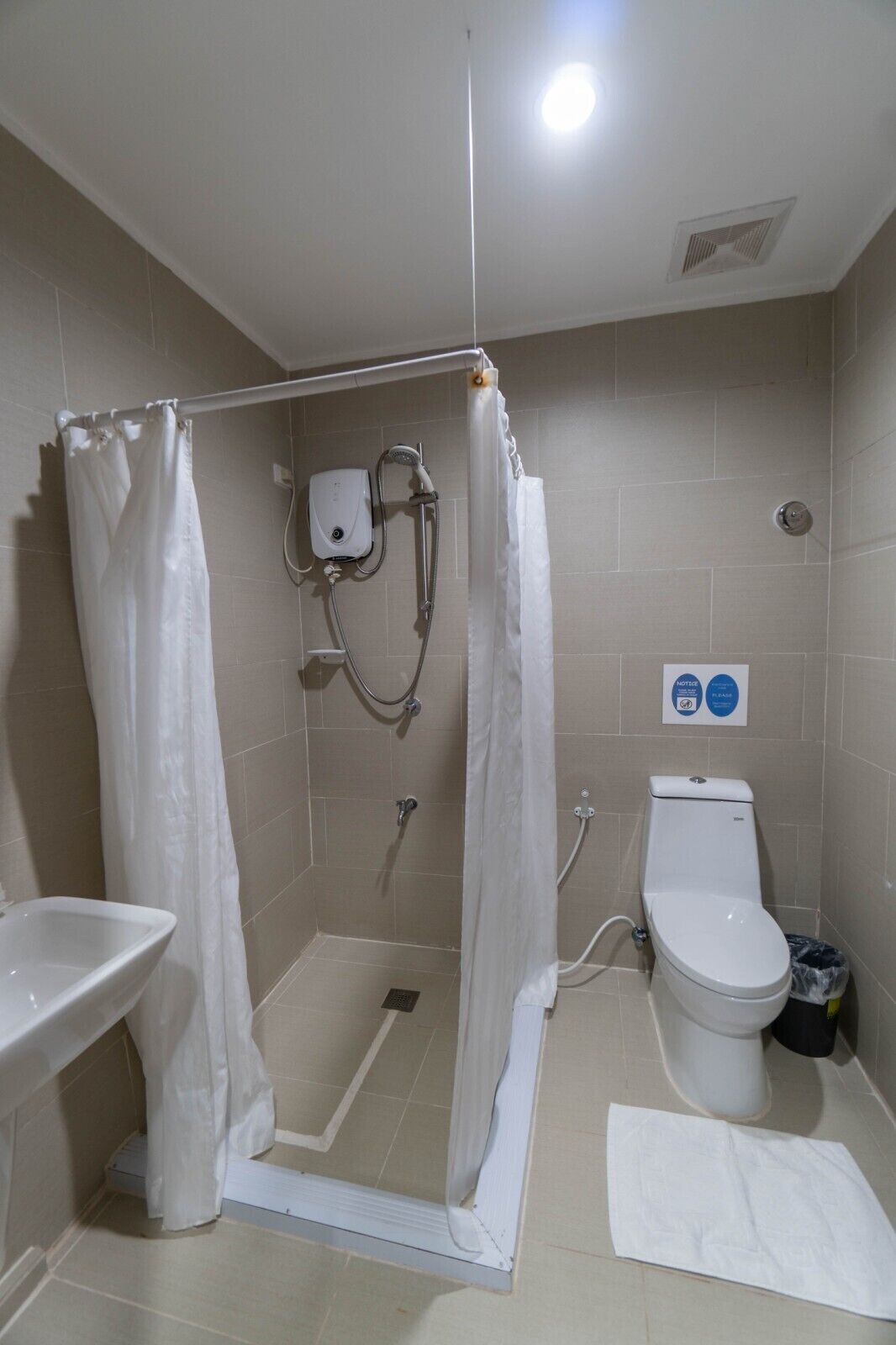 A bathroom with a shower enclosure, a toilet, and a sink.
