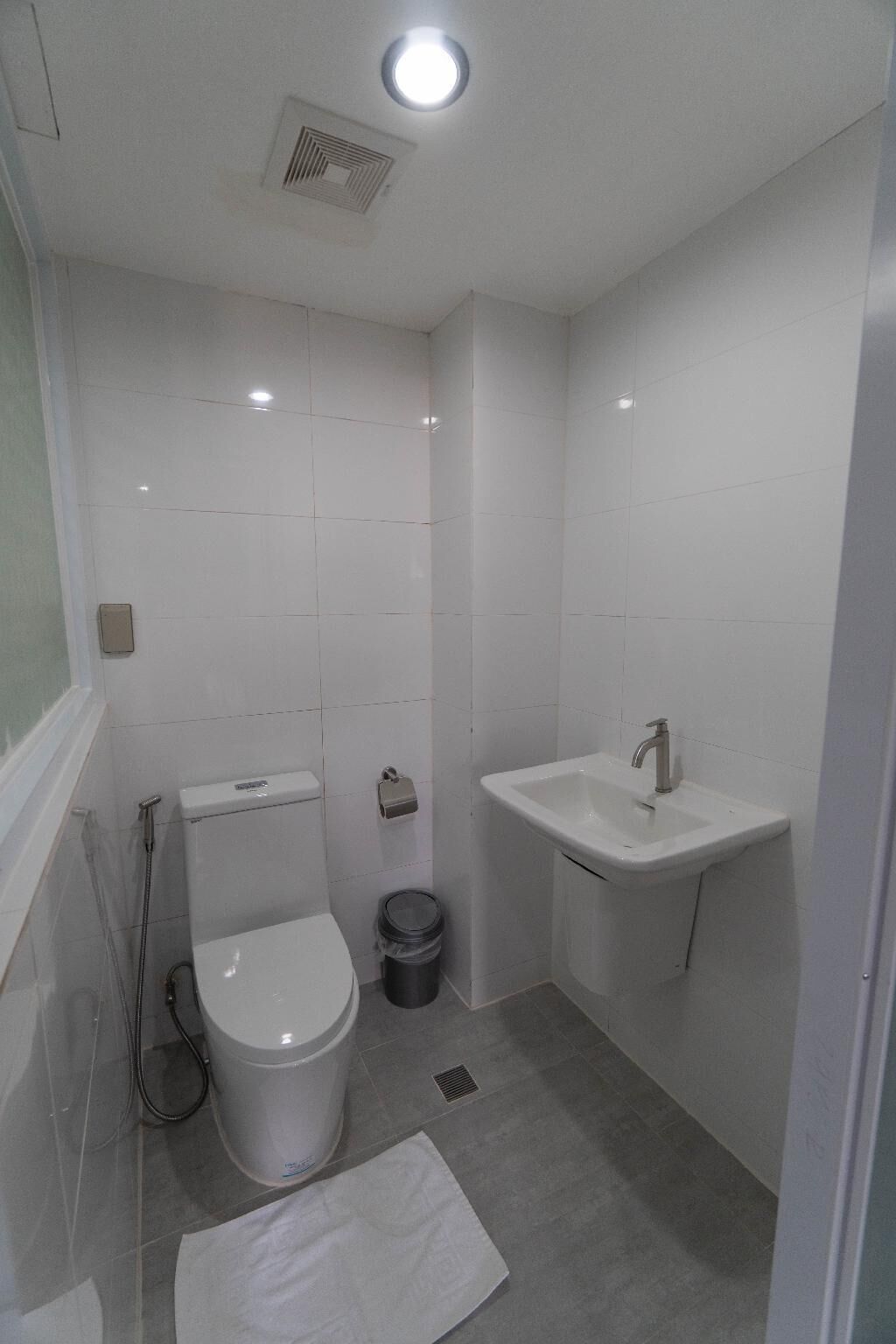 Une petite salle de bain moderne, équipée de toilettes, d’un lavabo et d’une douche.