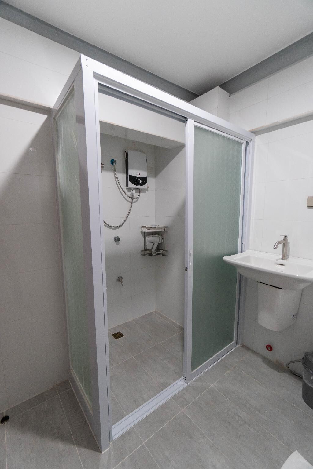A bathroom with a shower enclosure, a toilet, and a sink.