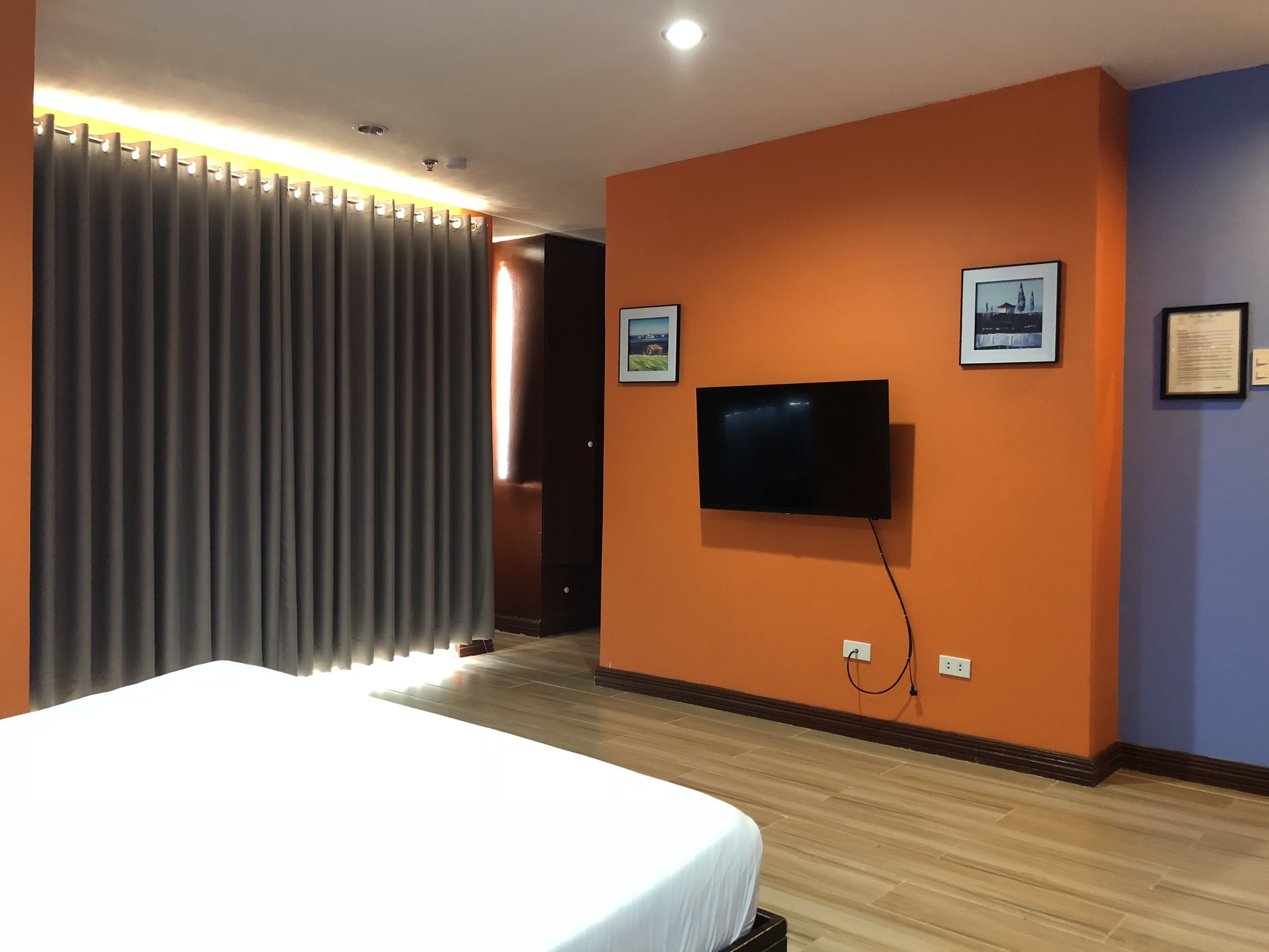 Une chambre d’hôtel avec un lit, un téléviseur à écran plat fixé au mur et une porte donnant sur une autre pièce.
