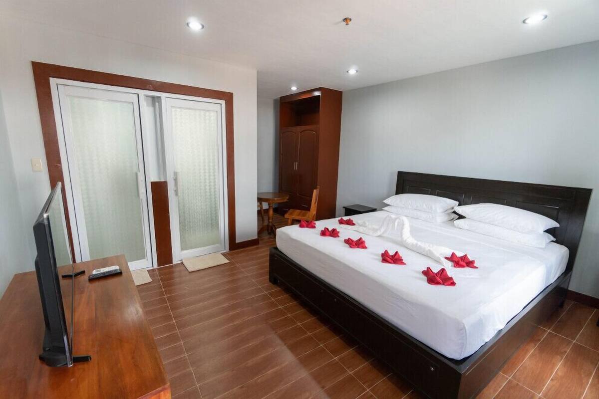 A hotel room with a large bed, a TV, a wardrobe, and a desk.