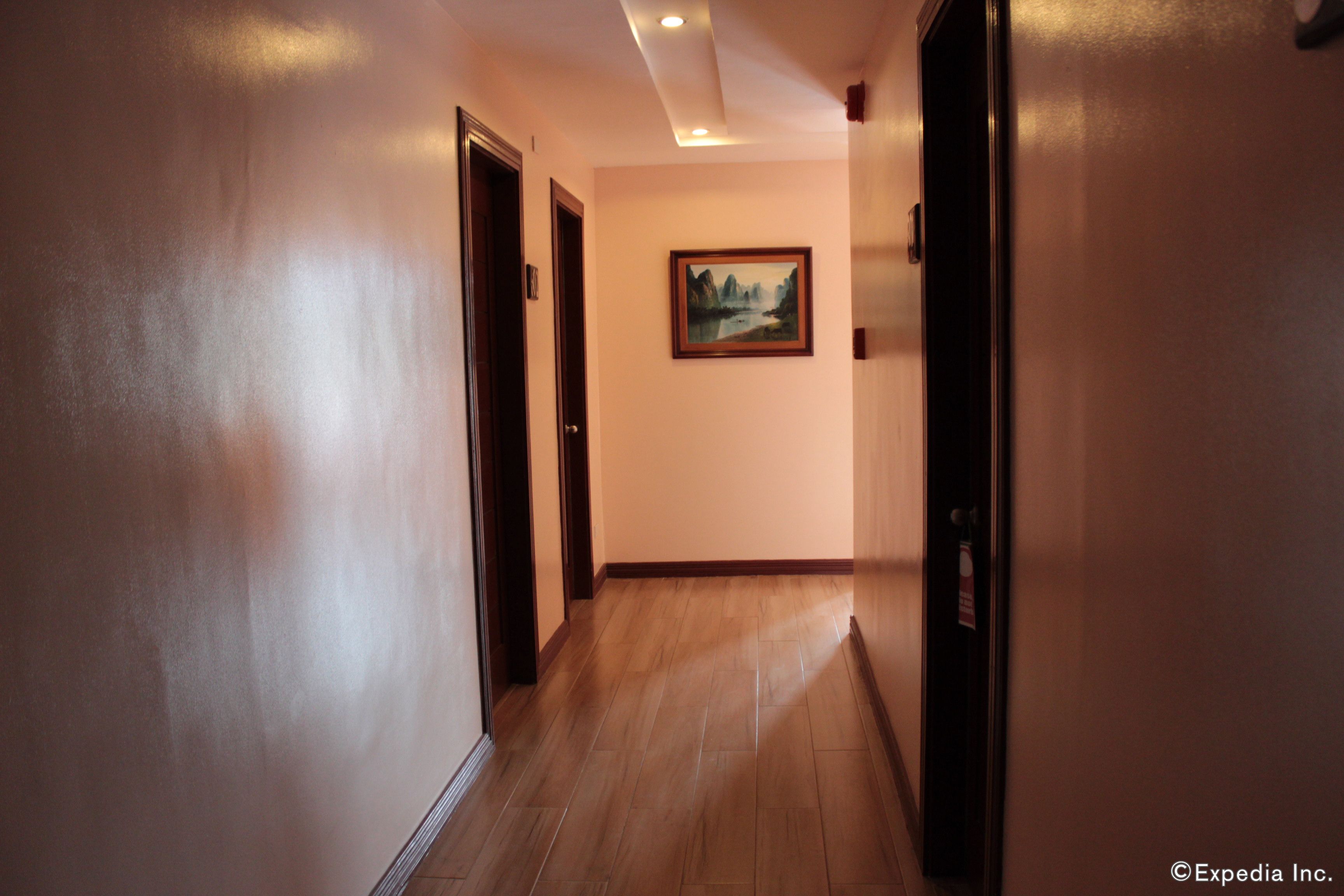 A hallway with wooden flooring, a painting on the wall, and doors on both sides.