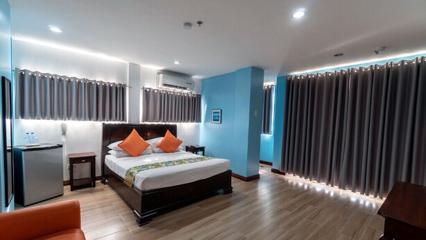 A modern hotel room with a large bed, a desk, and a chair. - One Averee Bay Hotel (Coron)