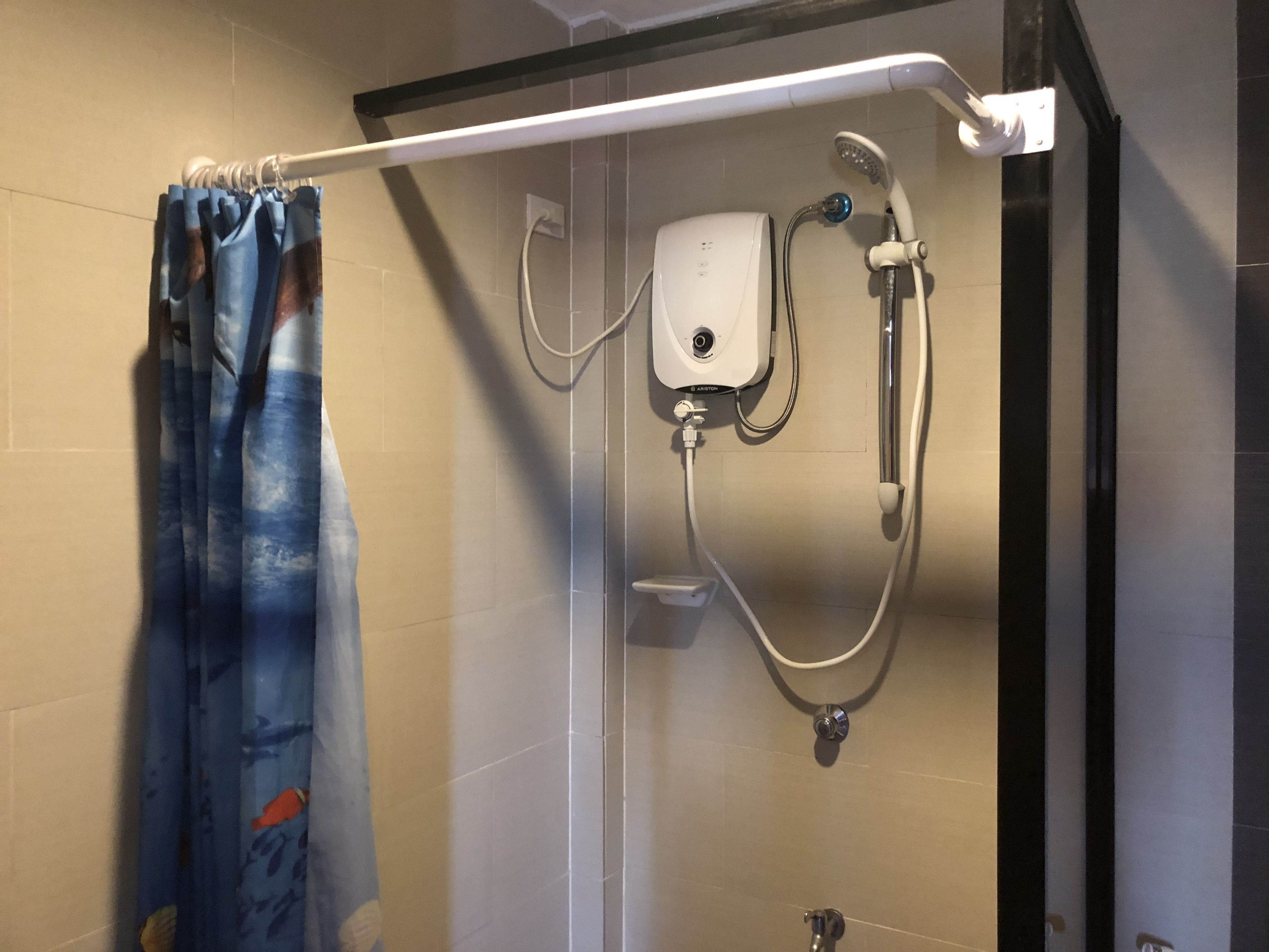 Een douche met een handdouche, een losse douchekop en een bedieningspaneel aan de muur.