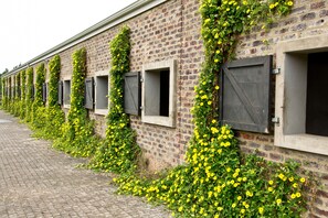 A brick building with multiple windows, some with shutters, and a brick pathway in front. - Kay and Monty Vineyard View (The Crags)