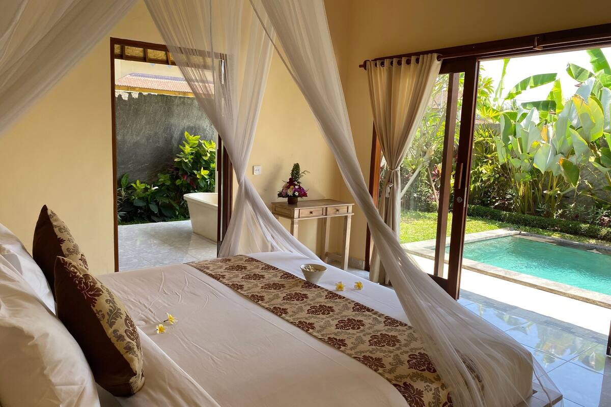 Un dormitorio con cama, mesita de noche y vista a una piscina.