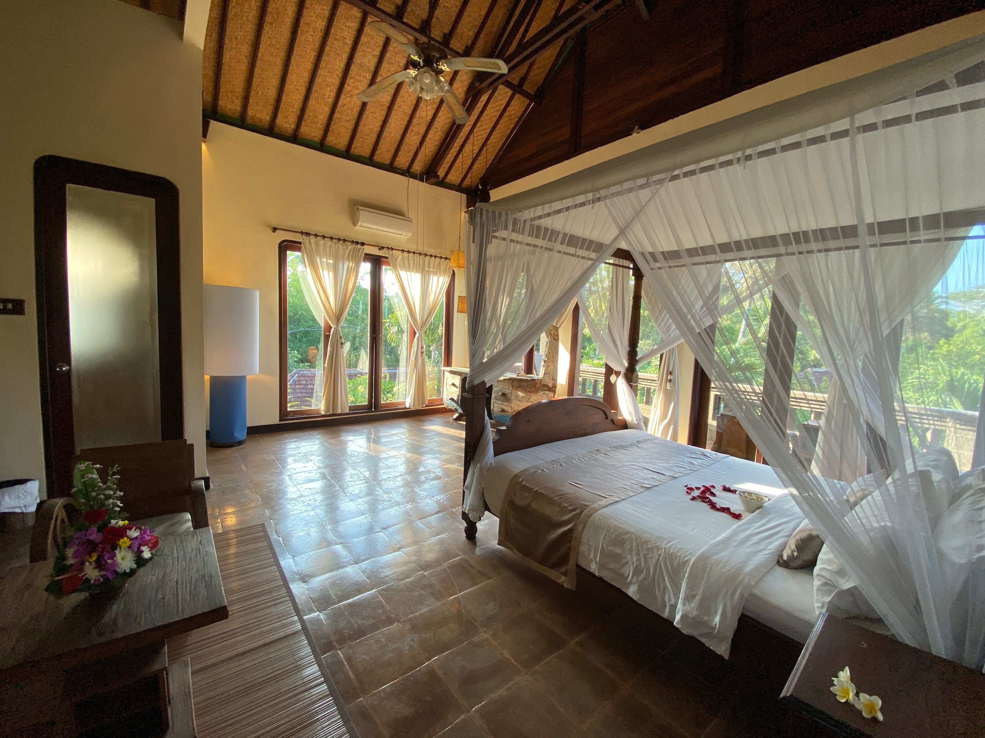 A bedroom with a bed, a wooden headboard, a nightstand, and a mirror.