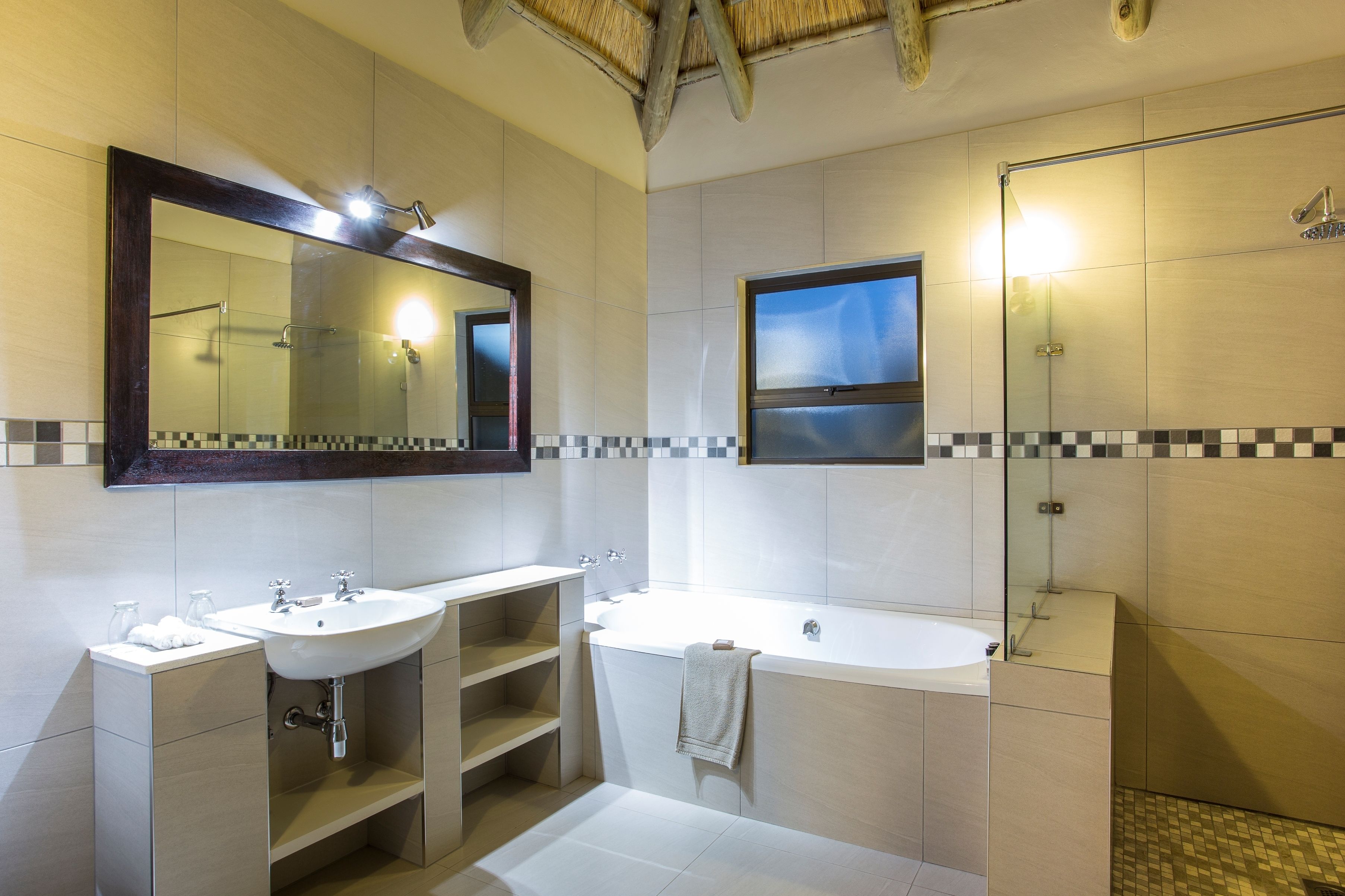 A modern bathroom with two sinks, a large bathtub, and a glass-enclosed shower.