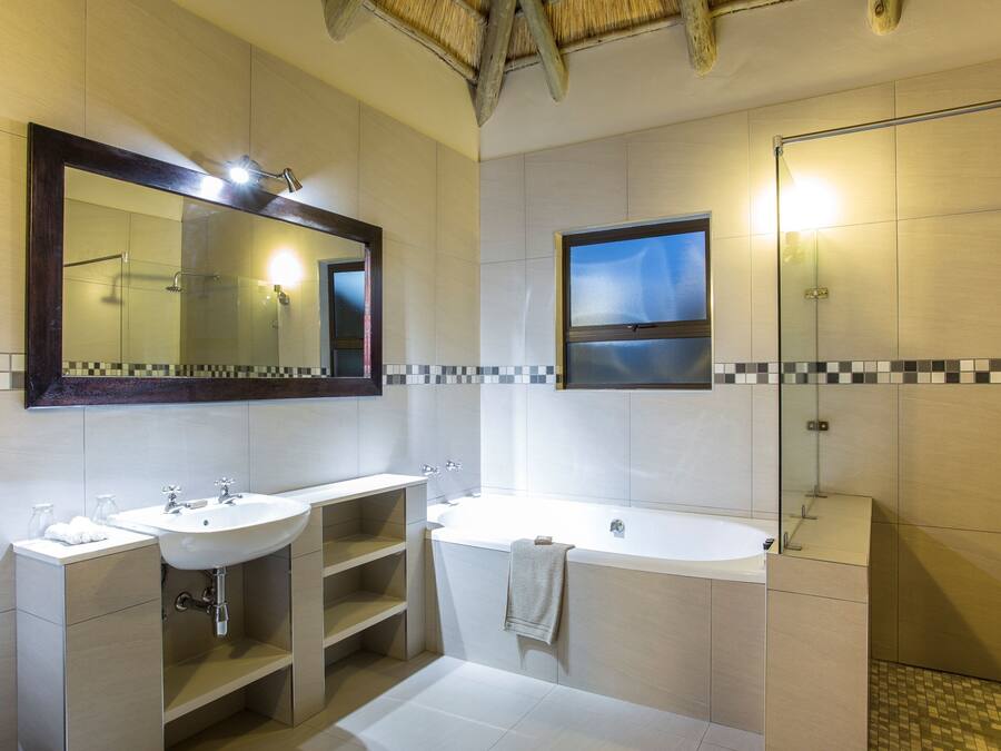 A modern bathroom with two sinks, a large bathtub, and a glass-enclosed shower.
