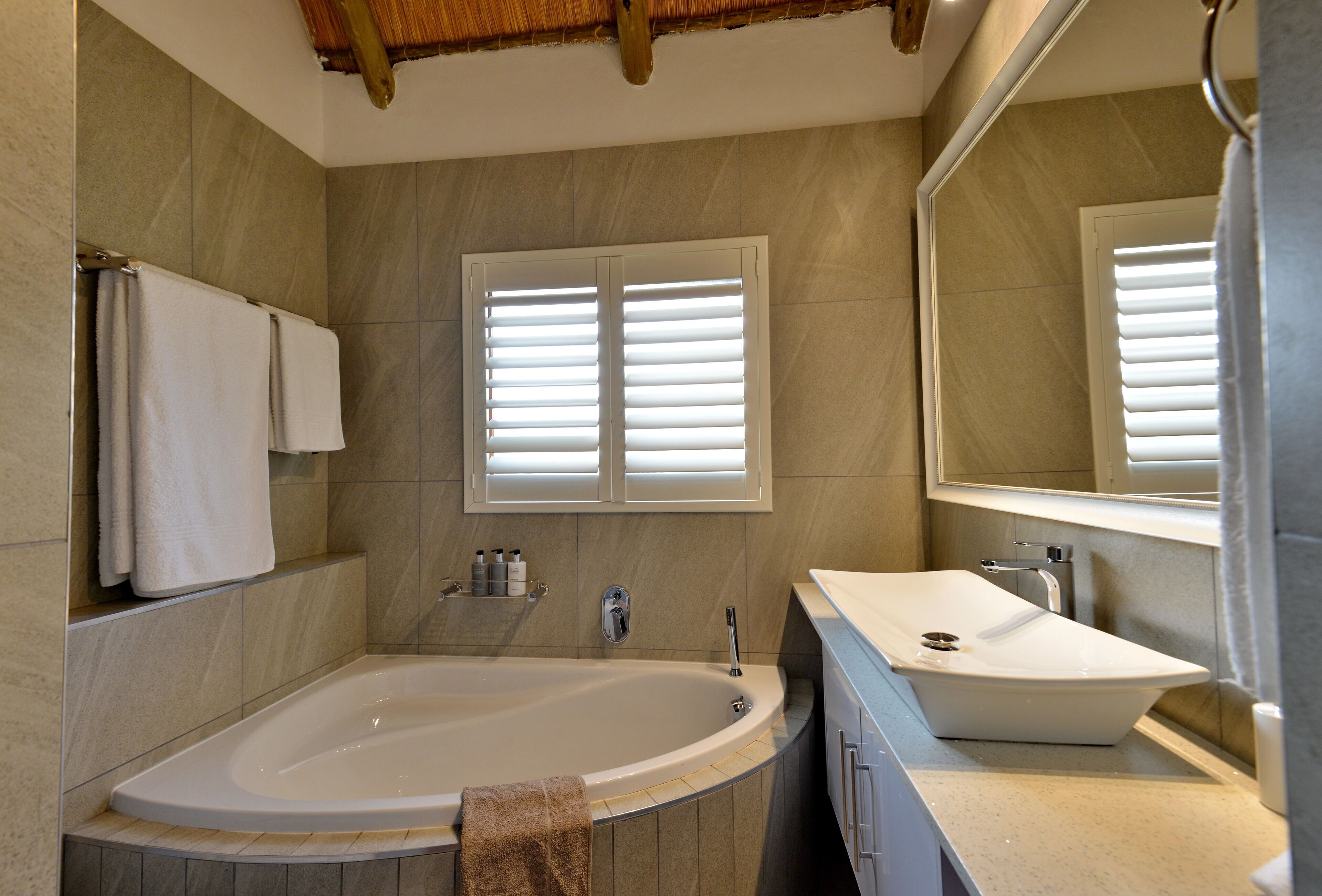 A modern bathroom with a freestanding bathtub, a sink, and a large mirror.