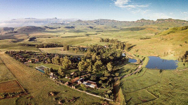 A rural landscape with a small cluster of houses surrounded by fields and a pond. - Montusi Mountain Lodge (Jagersrust)