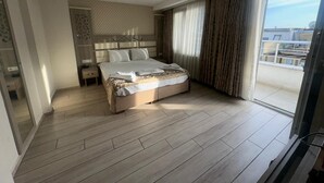 Una habitación de hotel moderna con una cama grande, un vestidor y un balcón con vistas.